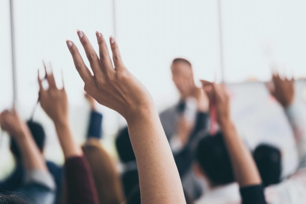 Audience raising hands at a business meeting